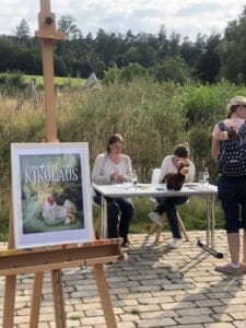 Buch " Der etwas andere Nikolaus " steht vor einem Tisch, an dem Exemplare von " Elsa büxt aus " signiert werden
