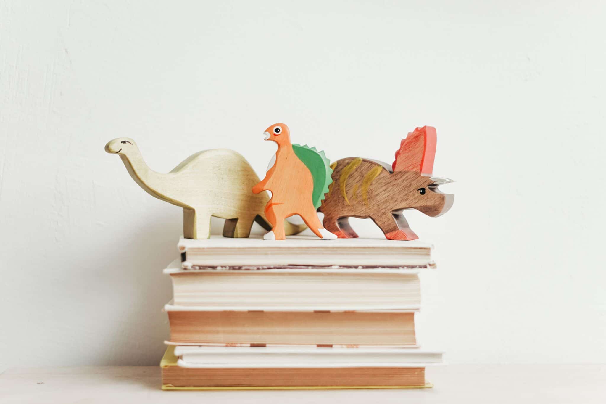 Dinosaurier-Figuren auf einem Stapel Bücher; Spielend Lesen lernen Unterstützung für Kinder