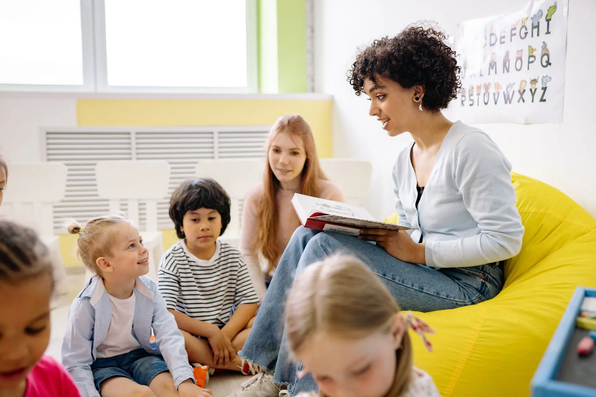 Frau liest Kindern etwas im Klassenzimmer vor