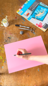 Hand malt mit Stift auf pinkem Blatt Papier