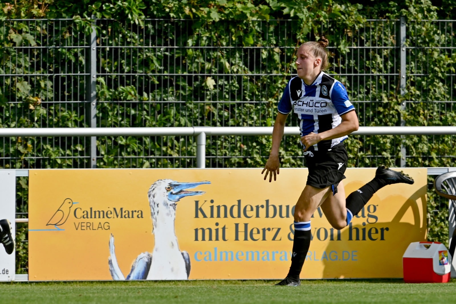Fußballerin läuft vor der CalmeMara-Bande auf dem Fußballplatz