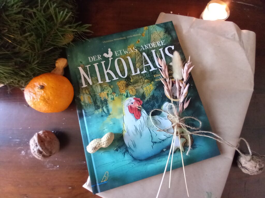 das Buch "Der etwas andere Nikolaus" mit zusammengeknoteten Blumen, Nüssen, einer Kerze, einer Orange und Geschenkpapier daneben