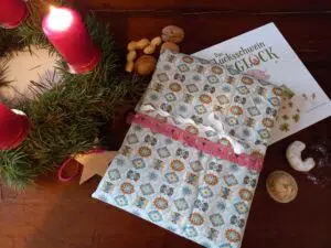 ein verpacktes Weihnachtsgeschenk neben einem Weihnachtskranz