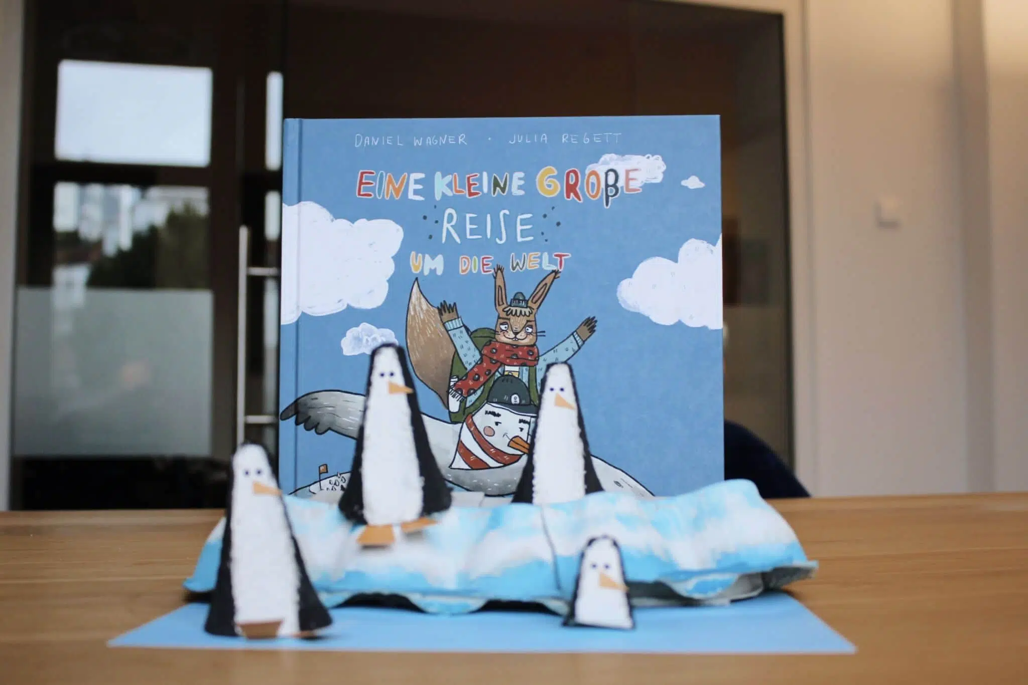 gebastelte Penguine stehen vor dem Buch "Eine kleine große Reise", ein paar der Pinguine stehen auf einer gebastelten Eisscholle