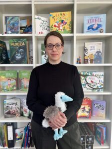 Anne_klein Eine Frau mit braunen Haaren und Brille hält unseren Verlagvogel Bo in den Händen