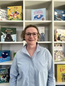 Birgit_klein Eine Frau mit Brille und blauer Bluse lächelt in die Kamera